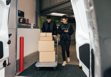 Two warehouse workers loading parcels into a delivery van.